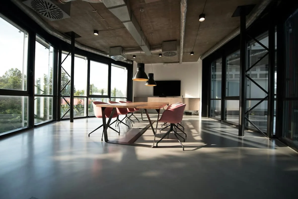 An empty boardroom with a long table and chairs beside a glazed wall.