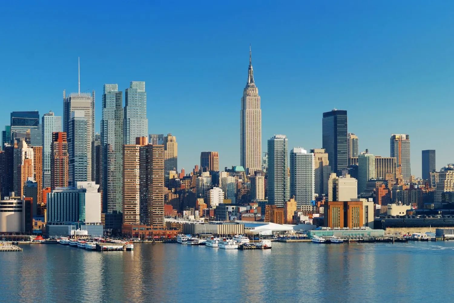 The Manhattan skyline across the water, with the Empire State Building rising above the surrounding towers.