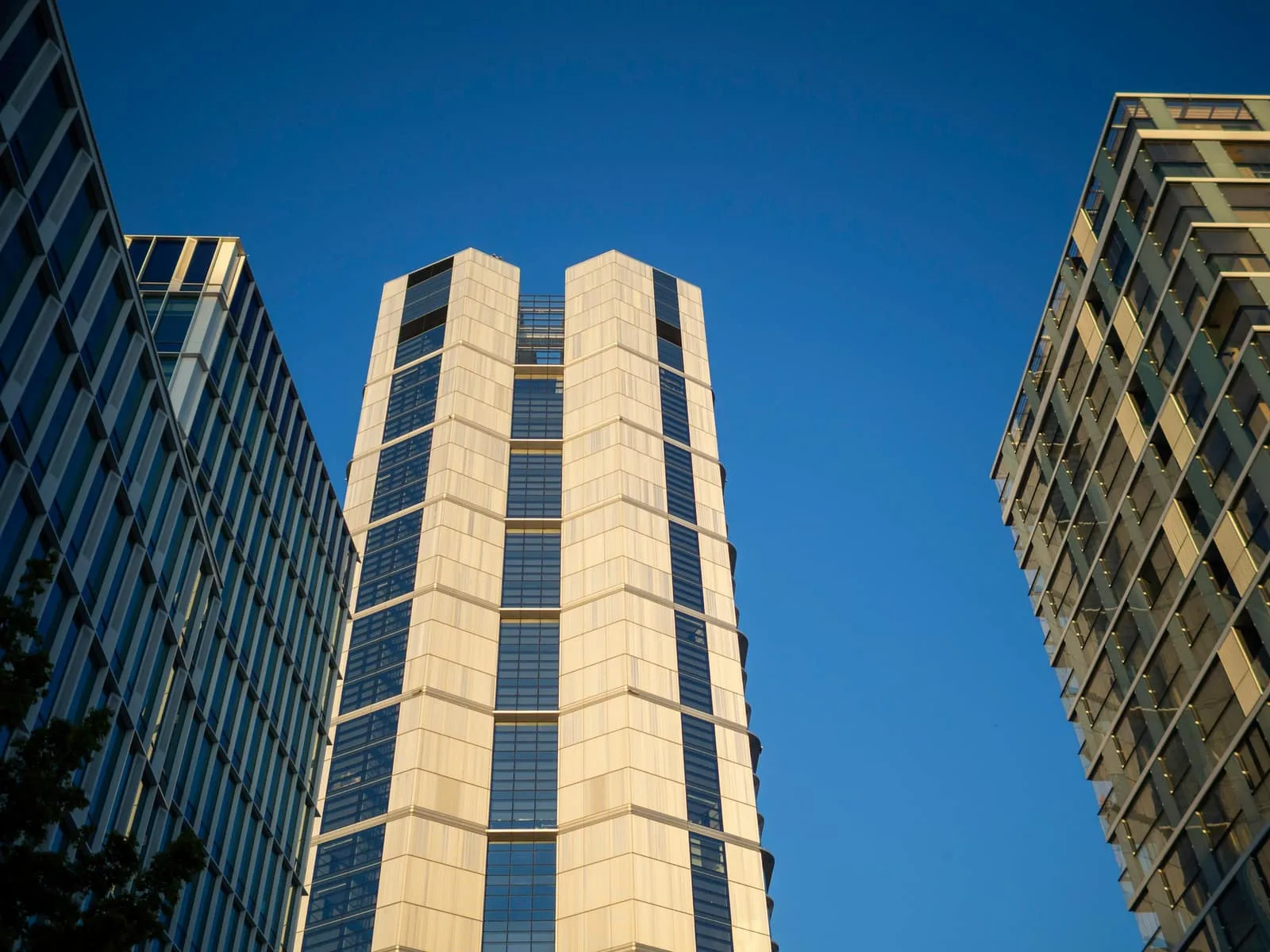 Three modern office towers seen from street level against a clear sky.